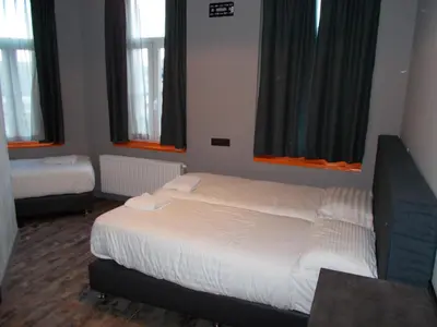 a bedroom with a bed with white sheets and windows at Urban City Centre Hostel in Brussels