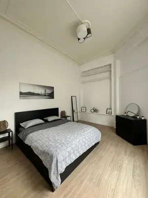 a white bedroom with a bed and a dresser and a bed sidx sidx sidx at Authentique appartement in Brussels