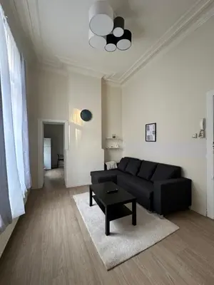 a living room with a black couch and a table at Authentique appartement in Brussels