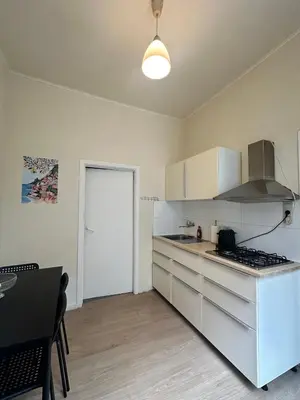 a kitchen with white cabinets and a stove top oven at Authentique appartement in Brussels