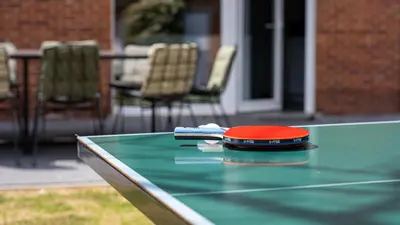 a ping pong table with a cell phone on it at Nethehuis in Kasterlee