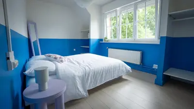 a blue bedroom with a bed and a table at Nethehuis in Kasterlee
