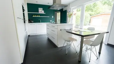 a kitchen with white cabinets and a table and chairs at Nethehuis in Kasterlee