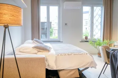 a bedroom with a bed and a lamp and windows at Garden View Apt in Ghent in Ghent