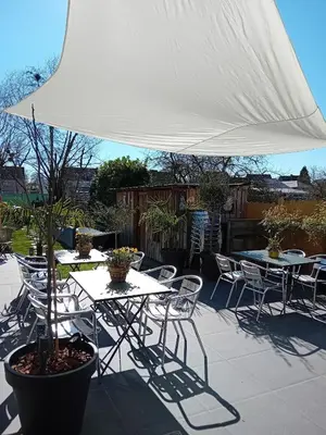 a patio with tables and chairs under a white umbrella at ' t Geel Huizeken - B&B - koffiehuis in Denderleeuw