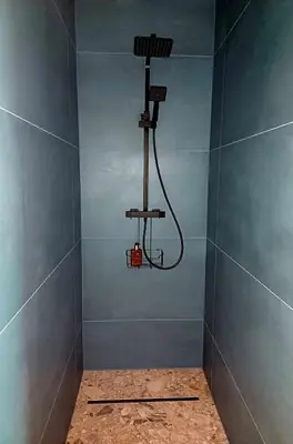 a shower in a blue bathroom with a hose at ' t Geel Huizeken - B&B - koffiehuis in Denderleeuw
