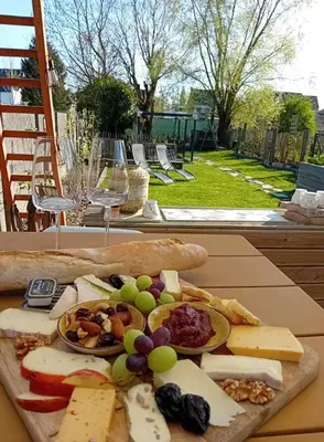 a plate of cheese and fruit on a table with wine glasses at ' t Geel Huizeken - B&B - koffiehuis in Denderleeuw