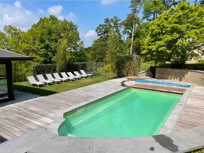 a swimming pool with lounge chairs in a backyard at Villa des Templiers - 20 min Brussels Airport in Wavre