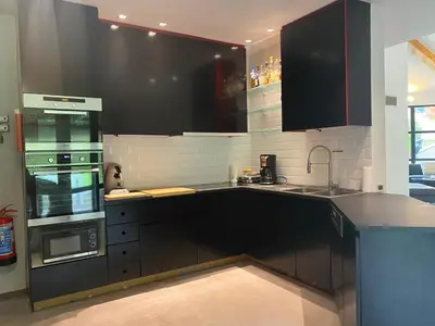 a kitchen with black cabinets and a sink and a stove at Villa des Templiers - 20 min Brussels Airport in Wavre