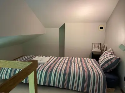 a bedroom with a bed with a striped comforter at Villa des Templiers - 20 min Brussels Airport in Wavre