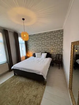 a bedroom with a large bed and a mirror at Vakantiewoning Huis 14 in Mechelen