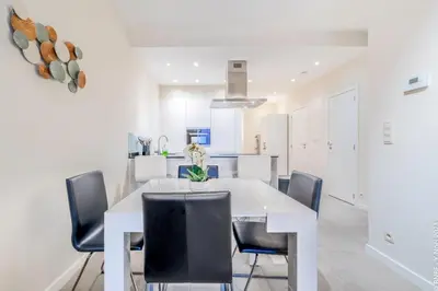 a white dining room with a white table and black chairs at Center of Antwerp - Fully Renovated - Private Indoor Parking in Antwerp