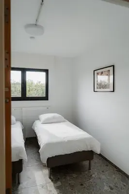 two beds in a white room with two windows at De Logé in Oud-Turnhout