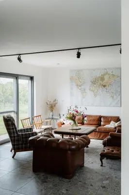 a living room with leather furniture and a map on the wall at De Logé in Oud-Turnhout