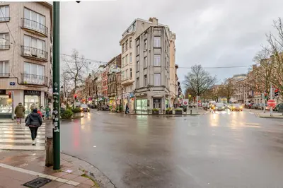 a woman walking down a city street in the rain at Le Joyau à Etterbeek in Brussels