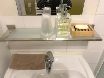 a bathroom sink with a glass shelf above it at Chère Anna City Center New Top location in Ghent