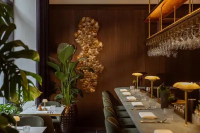 a long table in a restaurant with plants at Corinthia Grand Hotel Astoria Brussels in Brussels