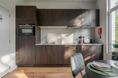 a kitchen with wooden cabinets and a table and a window at Moneta in Antwerp
