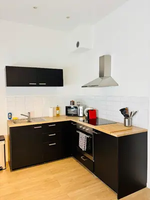 a kitchen with black cabinets and a stove top oven at Sublime appartement au centre de Bruxelles in Brussels