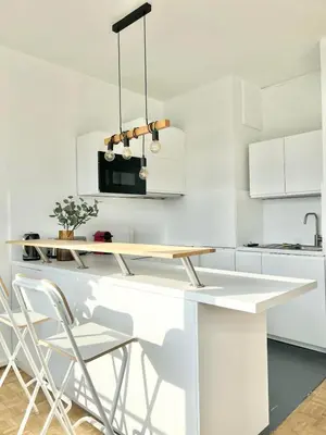 a white kitchen with a white counter and chairs at Petit cocon à Ixelles - Quartier Européen in Brussels