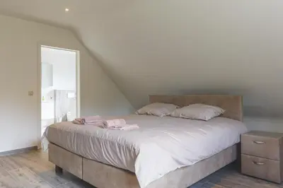 a bedroom with a large bed with pink clothes on it at Villa Remis in Sint-Denijs-Westrem