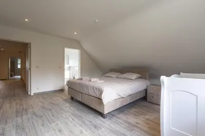 a bedroom with a large bed and wooden floors at Villa Remis in Sint-Denijs-Westrem
