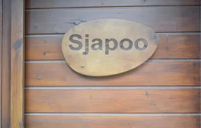 a sign on the side of a wooden wall at Sjapoo in Wachtebeke