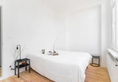 a white bedroom with a bed and two tables at Charming house in city center in Antwerp