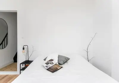 a white bed in a white room with a mirror at Charming house in city center in Antwerp