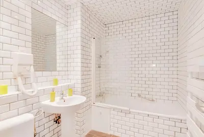 a white bathroom with a sink and a tub at Grand Place Charbon Residence in Brussels
