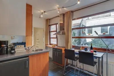 a kitchen with a table and two bar chairs at Grand Place Charbon Residence in Brussels