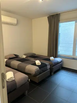 a hotel room with three beds and a window at Beautiful apartment in City Center in Brussels
