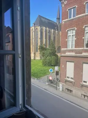 a window with a view of a street and a church at Art Studio Leuven in Leuven