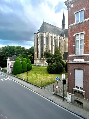 an old church with a grass yard in front of a street at Art Studio Leuven in Leuven