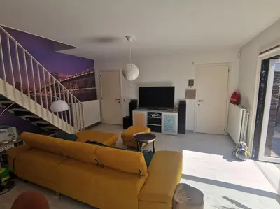 a living room with a couch and a staircase at Rustige ruime duplex in Wijnegem