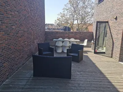 a patio with a table and chairs on a brick wall at Rustige ruime duplex in Wijnegem