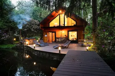 a cabin in the woods with a view of the water at ZenCabin - Luxe en Wellness in de natuur in Hulshout