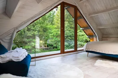 a bedroom with a bed and a large window at ZenCabin - Luxe en Wellness in de natuur in Hulshout