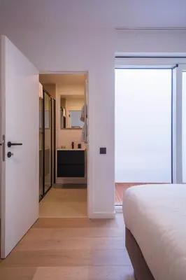 a bedroom with a white bed and a bathroom at Märch - Mechelen Goat 14 in Mechelen