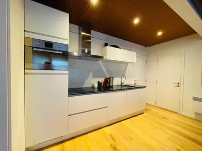 a kitchen with white cabinets and a wooden floor at Studio Intensity in Antwerp