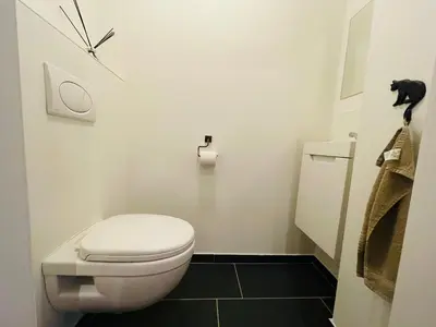 a bathroom with a toilet and a clock on the wall at Studio Intensity in Antwerp