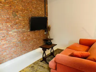 a living room with a couch and a tv on a brick wall at Living History - Suikernest in Antwerp