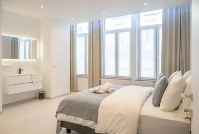 a white bedroom with a large bed with windows at Wonderful central 2BR Ghent apt w view on Leie in Ghent