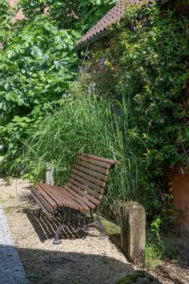 a park bench sitting in front of a bush at Cozy Retreat with Sauna near Gent-St-Pieters in Ghent