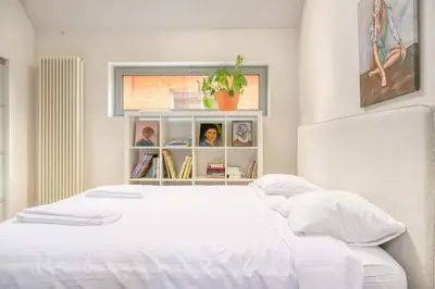 a bedroom with a white bed and a book shelf at Cozy Retreat with Sauna near Gent-St-Pieters in Ghent