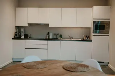 a kitchen with a wooden table and white cabinets at Modern home near Ghent - Easy Access, Ideal Living in Ghent