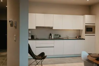 a kitchen with white cabinets and a chair in a room at Modern home near Ghent - Easy Access, Ideal Living in Ghent