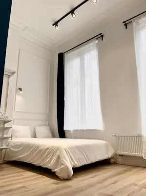 a white bedroom with a bed and two windows at Chez Gianni & Stéphanie - A cozy and elegant Studio in Brussels in Brussels