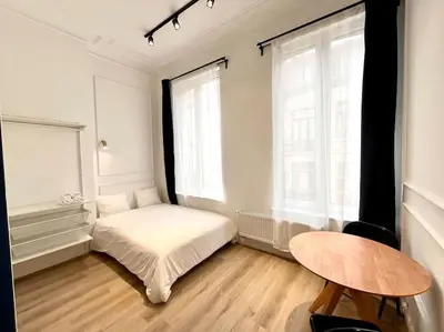 a white bedroom with a bed and a table at Chez Gianni & Stéphanie - A cozy and elegant Studio in Brussels in Brussels