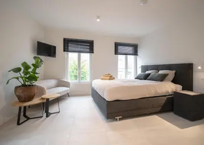 a bedroom with a large bed and a chair at Mavue kamer met terras in Mechelen